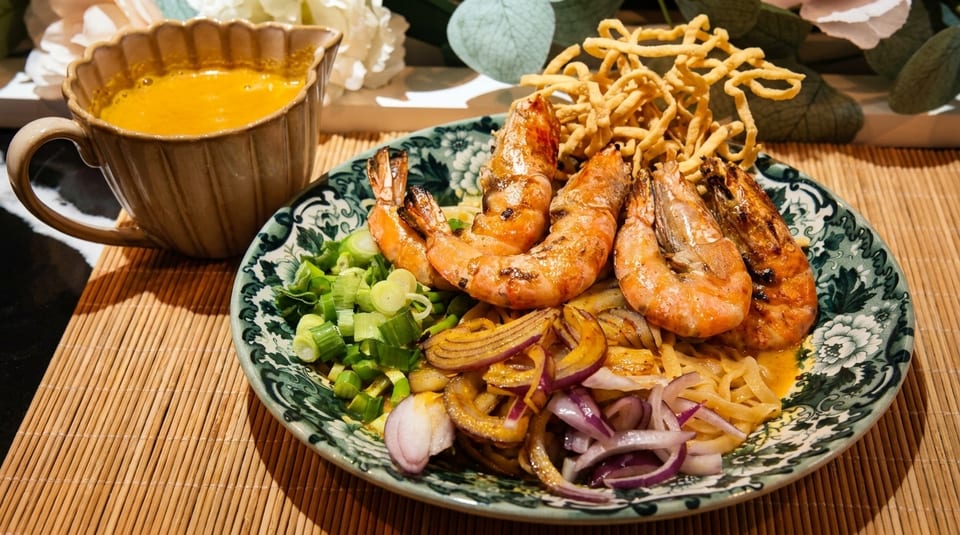 Khao Soi with grilled prawns, crispy noodles, red onions, and scallions, served with curry sauce.